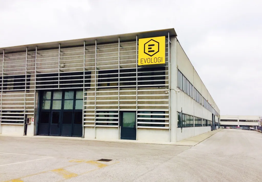 La sede operativa Evologi: facciata in cemento e acciaio con l'insegna esagonale dorata del marchio